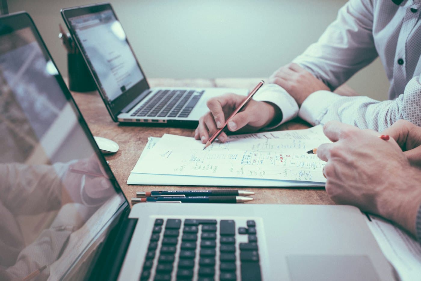 Two people reviewing financial plans on paper next to laptops