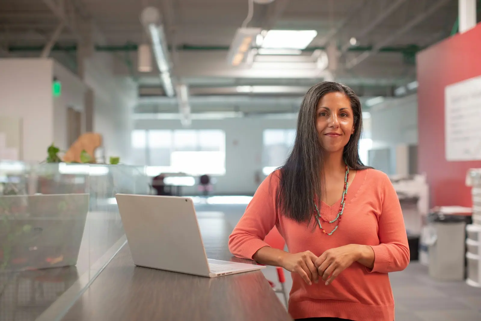 A woman standing by her laptop in a bright open office